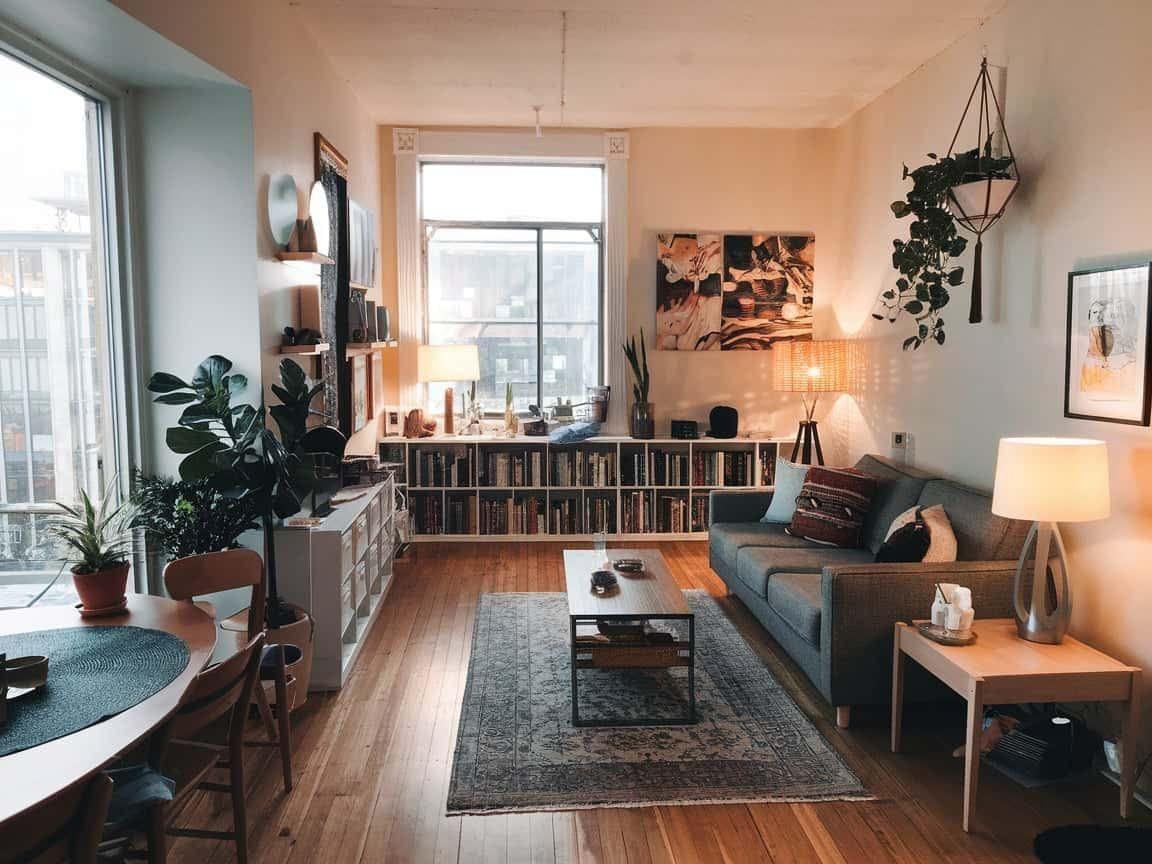 Warm small apartment living room with low bookshelves and plants